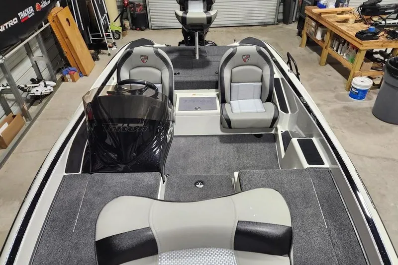 Slide: The Image of 2026 Triton 179 TrX boat interior with seating and steering console in a garage setting. - 4