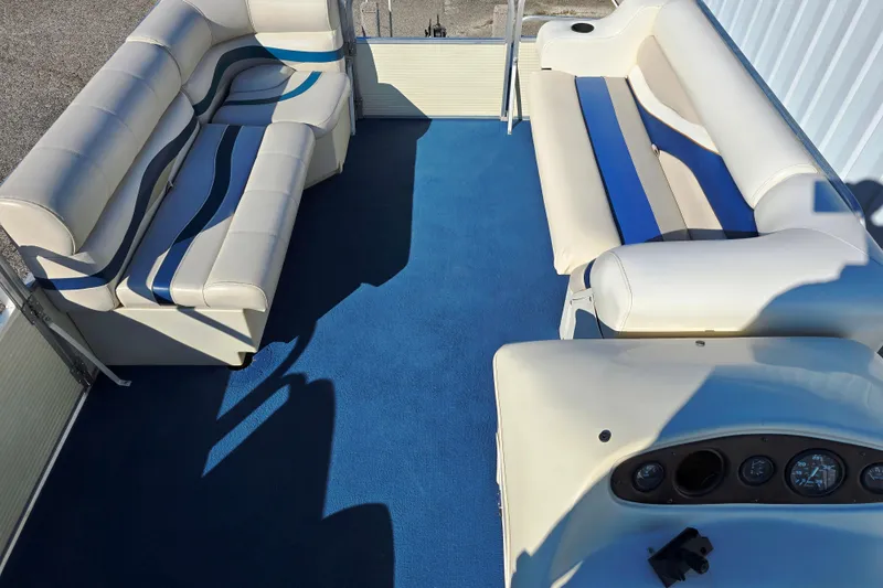 Slide: The Image of Interior of a 1999 Lowe Trinidad 220 pontoon boat with blue carpet and white seating. - 5
