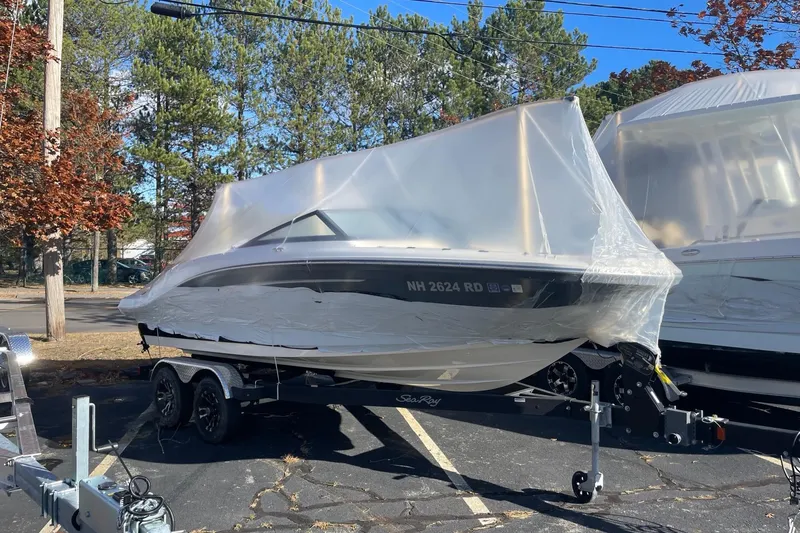 The Image of 2022 Sea Ray SPX 190 boat covered in plastic wrap on a trailer, parked outdoors. - 2