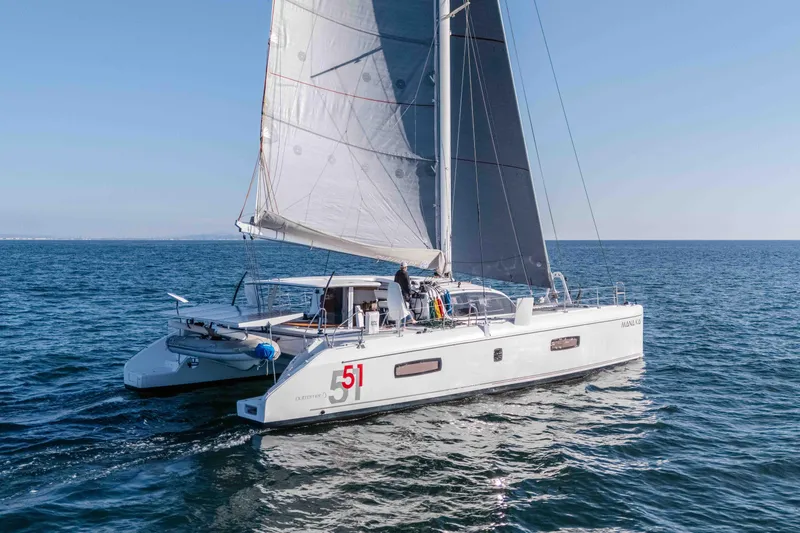 The Image of 2014 Outremer 51 catamaran sailing on open sea under clear blue sky. - 1