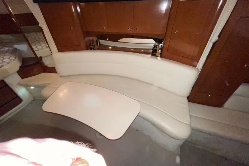 Slide: The Image of 2003 Sea Ray 340 Sundancer interior with curved seating and table, featuring wood cabinetry. - 21