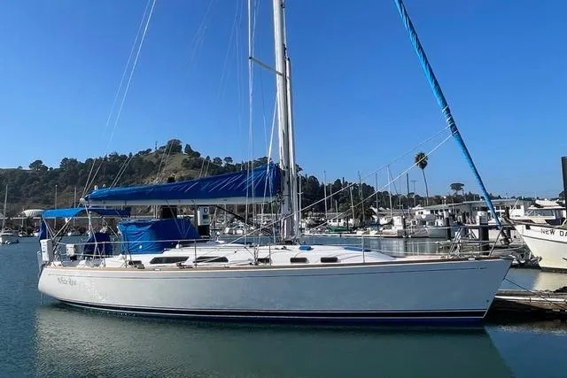 Slide: The Image of 2004 Sabre 426 sailboat "White Rose" docked in a marina, featuring blue covers. - 1
