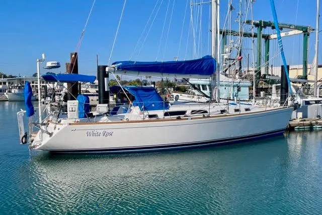 Slide: The Image of 2004 Sabre 426 sailboat docked in marina, named "White Rose," with blue sail cover. - 3