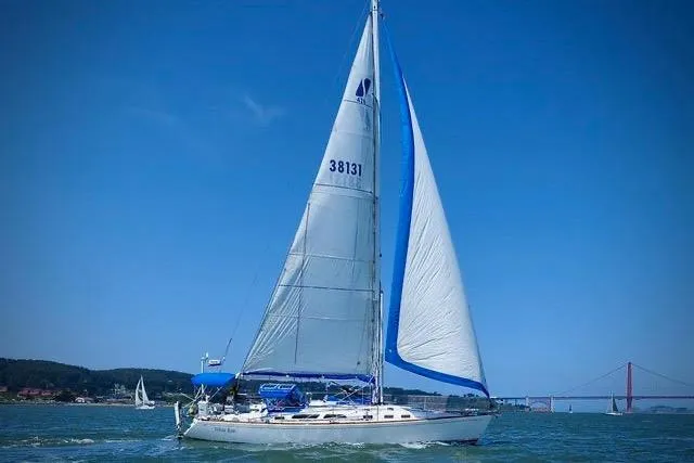 Slide: The Image of Sailboat Sabre 426 (2004) on water with mountainous backdrop and cloudy sky. - 6