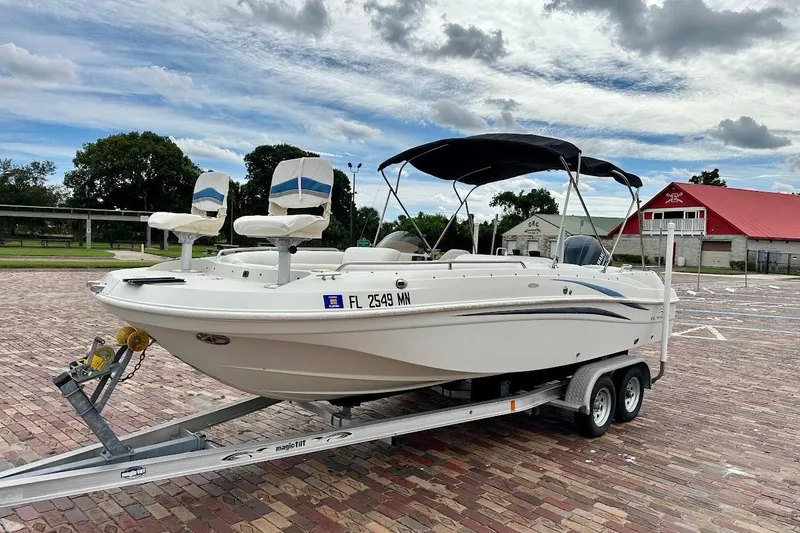 Slide: The Image of 2004 Bennington RL 210 boat on trailer, parked on brick pavement under cloudy sky. - 5