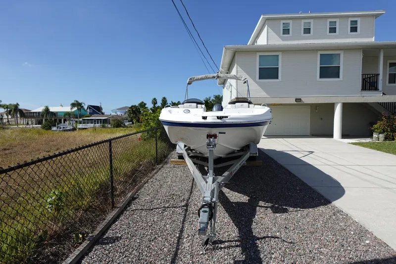 Slide: The Image of 2021 Hurricane Sundeck Sport 218 OB boat parked beside a modern house. - 3