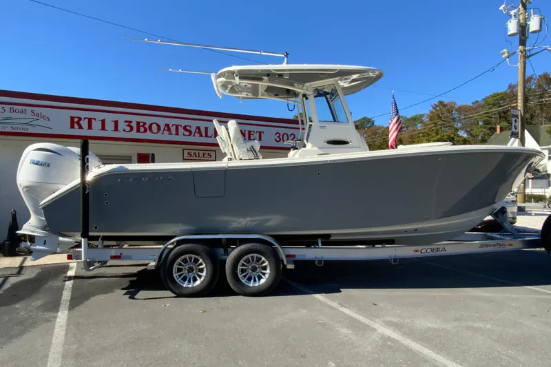The Image of 2026 Cobia 265 Center Console boat on trailer at dealership, sunny day. - 1