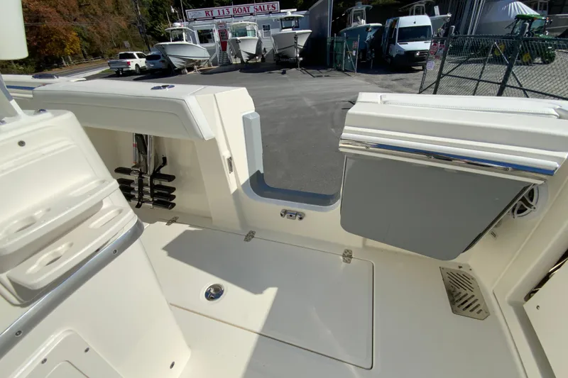 Slide: The Image of 2026 Cobia 265 Center Console boat interior with storage and rod holders at a sales lot. - 26
