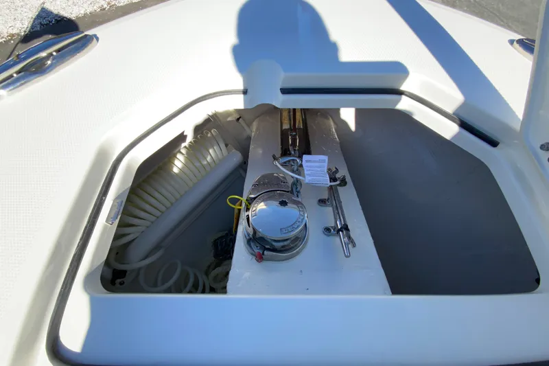 Slide: The Image of 2026 Cobia 265 Center Console boat storage compartment with coiled hose and equipment. - 32