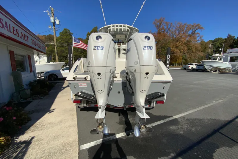 Slide: The Image of 2026 Cobia 265 Center Console boat with dual 200 horsepower engines, parked outdoors. - 8