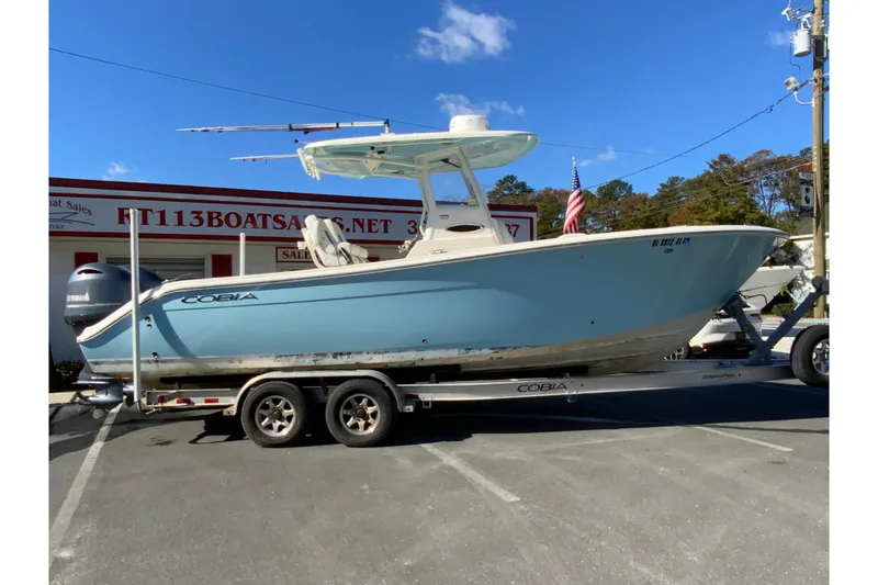 The Image of 2019 Cobia 262 Center Console boat on trailer, parked outside dealership. - 1