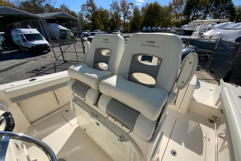 Slide: The Image of 2019 Cobia 262 Center Console boat with dual cushioned seats, docked outdoors. - 14