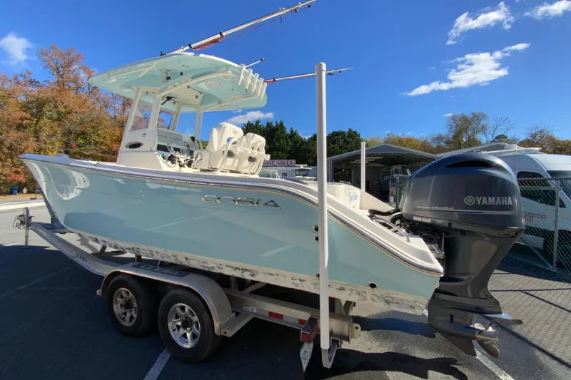 Slide: The Image of 2019 Cobia 262 Center Console boat on trailer with Yamaha engine, under clear blue sky. - 7