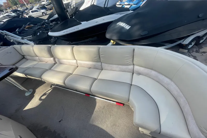Slide: The Image of 2013 Bennington R22 boat with spacious beige seating and nearby covered watercraft. - 6