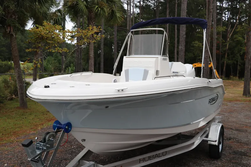 Slide: The Image of 2026 Robalo R180 Center Console boat on trailer, surrounded by trees. - 2