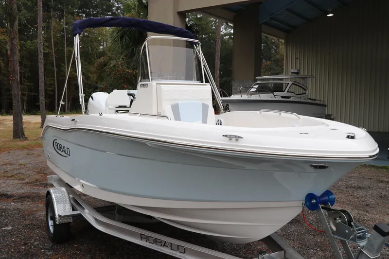 Slide: The Image of 2026 Robalo R180 Center Console boat on trailer, parked outdoors. - 3