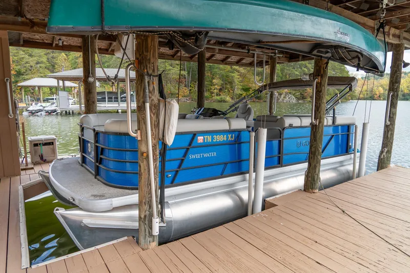 The Image of 2021 Godfrey Sweetwater 2286 C pontoon boat docked in a serene lakeside setting. - 1