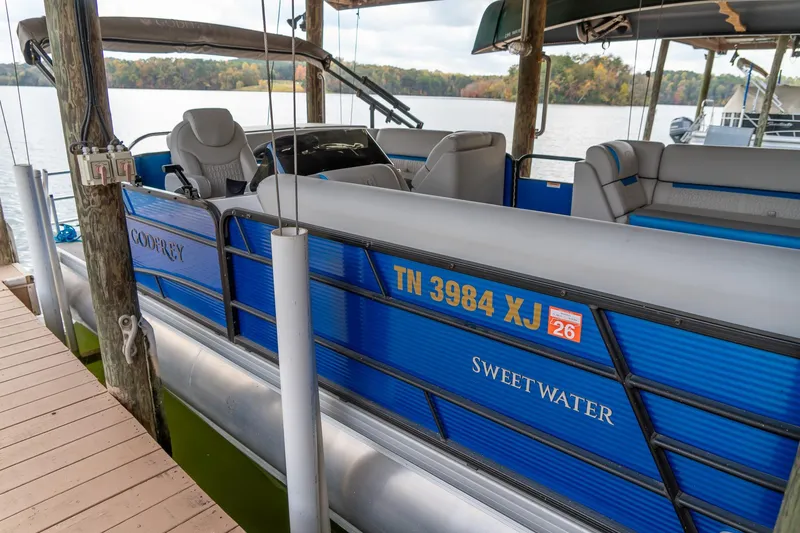 Slide: The Image of 2021 Godfrey Sweetwater 2286 C pontoon boat docked by a scenic lake. - 5