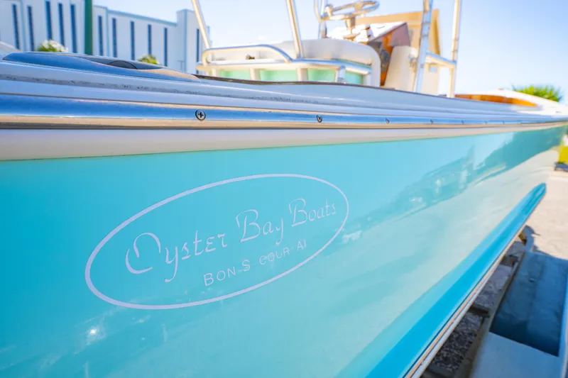 Slide: The Image of Turquoise 2005 Oyster Bay 23 boat with logo, parked outdoors on a sunny day. - 13