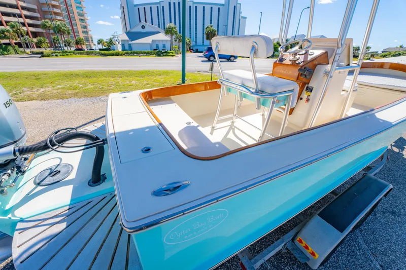 Slide: The Image of 2005 Oyster Bay 23 boat on trailer, parked near modern buildings and road. - 15