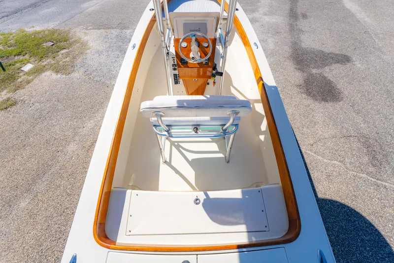 Slide: The Image of 2005 Oyster Bay 23 boat interior with wooden accents and steering console. - 24