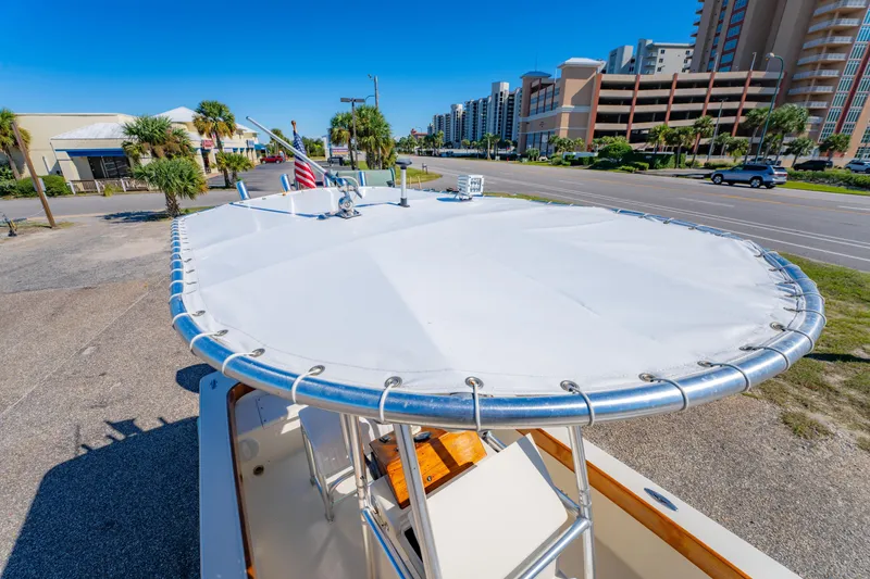 Slide: The Image of 2005 Oyster Bay 23 boat with covered deck, parked near coastal buildings and road. - 30