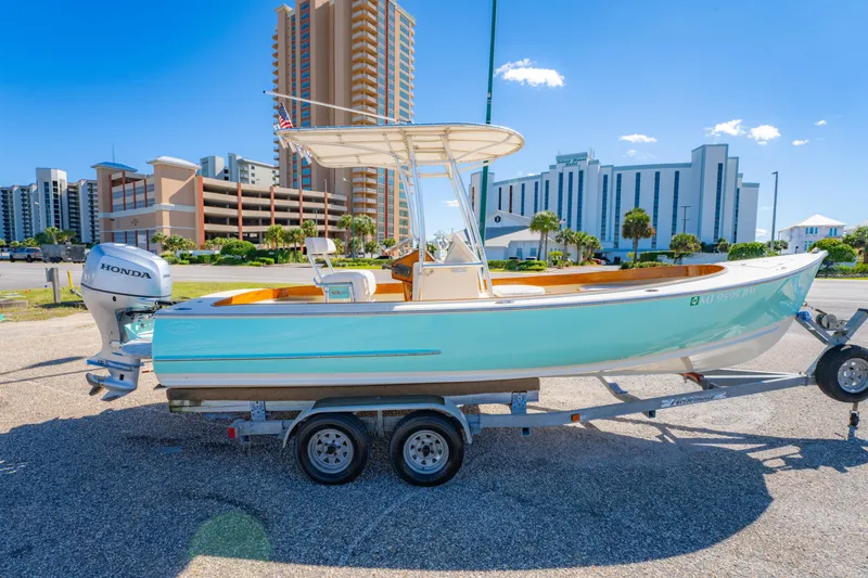 Slide: The Image of 2005 Oyster Bay 23 boat on trailer, parked near modern buildings under clear blue sky. - 7
