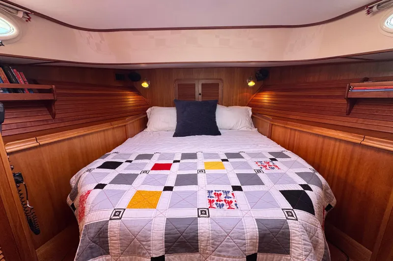 Slide: The Image of Cozy cabin interior of 2001 Hinckley Talaria 44 with quilted bed and wooden paneling. - 3