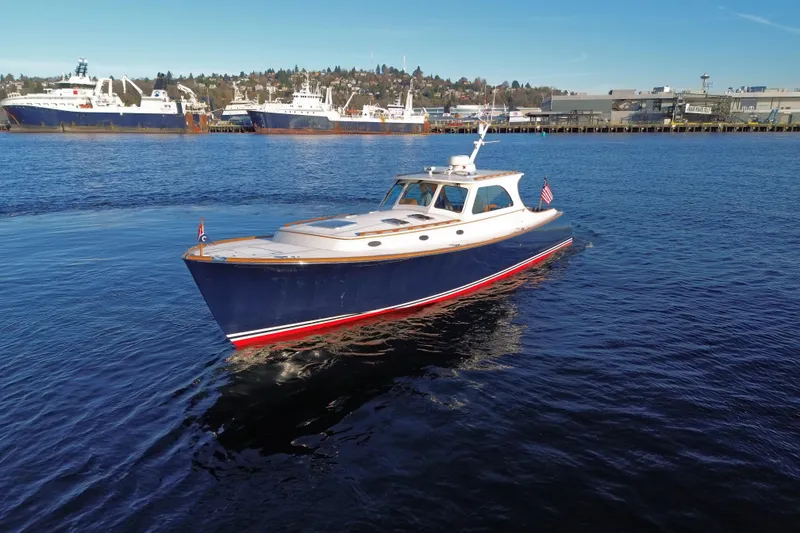Slide: The Image of 2001 Hinckley Talaria 44 yacht cruising in a harbor with ships in the background. - 60