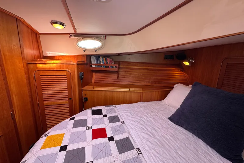 Slide: The Image of Cozy cabin interior of 2001 Hinckley Talaria 44 with quilted bedding and wooden accents. - 31