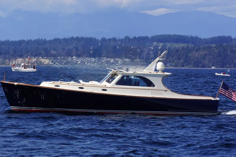Slide: The Image of 2001 Hinckley Talaria 44 yacht cruising on a scenic lake with forested hills. - 58