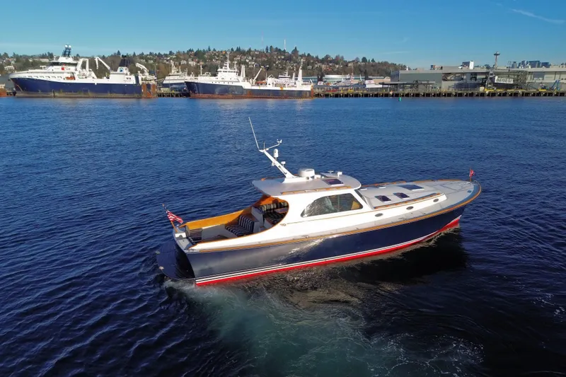 Slide: The Image of 2001 Hinckley Talaria 44 yacht cruising in a harbor with ships in the background. - 61