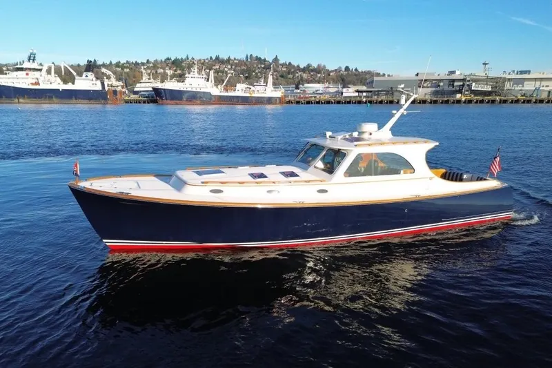 Slide: The Image of 2001 Hinckley Talaria 44 yacht cruising on calm waters near a harbor. - 62