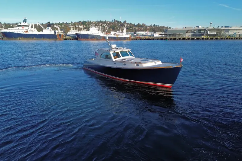 Slide: The Image of 2001 Hinckley Talaria 44 yacht cruising in a harbor with ships in the background. - 65