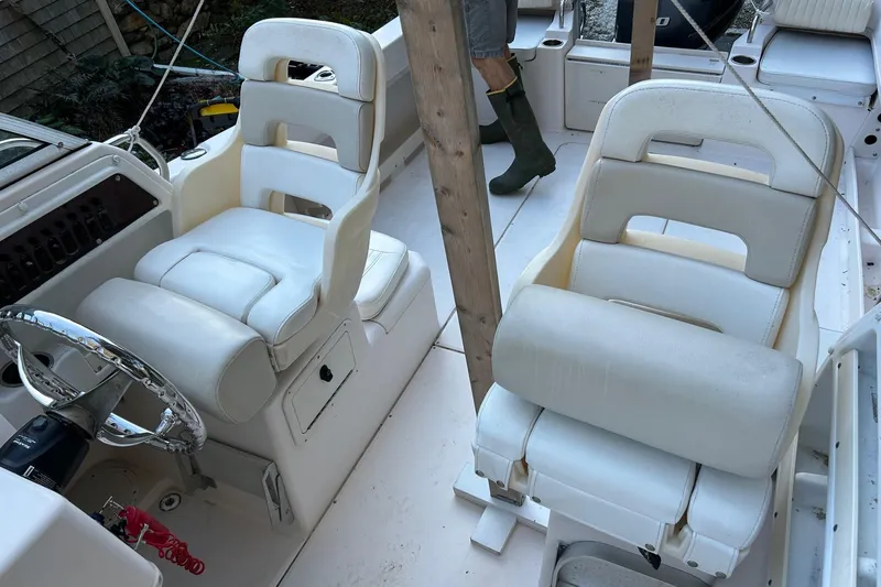 Slide: The Image of 1998 Grady-White Seafarer 226 boat interior with white cushioned seats and steering wheel. - 12