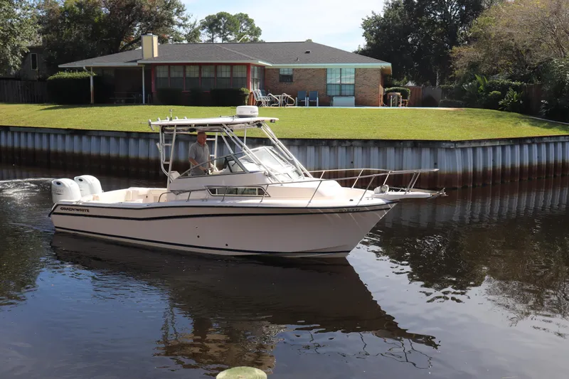 Slide: The Image of 1999 Grady-White Islander 268 boat cruising on a calm canal near a house. - 42