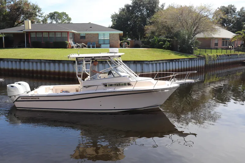 Slide: The Image of 1999 Grady-White Islander 268 boat cruising on a calm river near residential homes. - 43