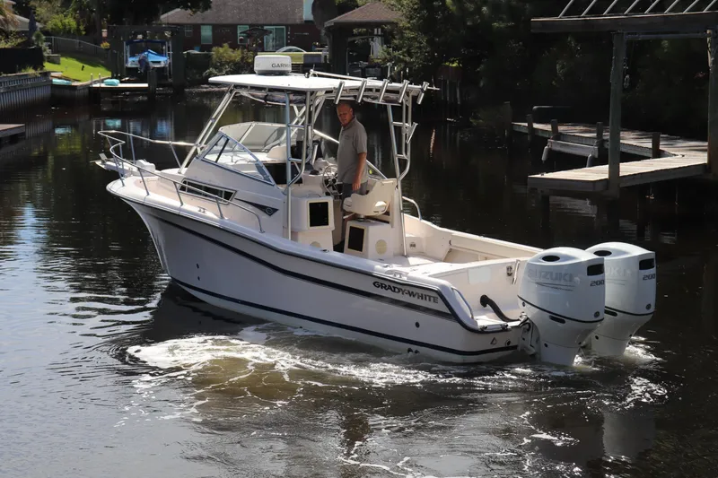 Slide: The Image of 1999 Grady-White Islander 268 boat with dual Suzuki engines on a calm waterway. - 49
