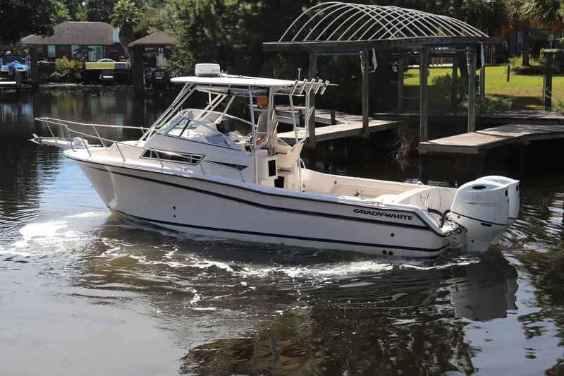 Slide: The Image of 1999 Grady-White Islander 268 boat cruising on a calm waterway near a dock. - 50