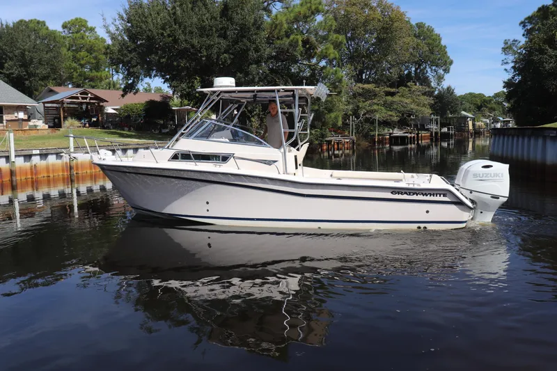 Slide: The Image of 1999 Grady-White Islander 268 boat on calm water, surrounded by trees and houses. - 54
