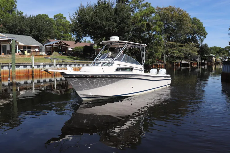 Slide: The Image of 1999 Grady-White Islander 268 boat on a calm waterway, surrounded by trees and houses. - 57