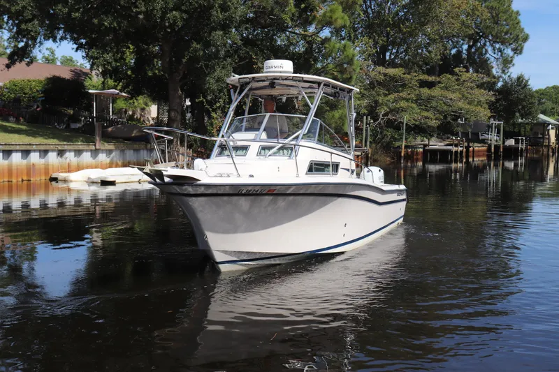 Slide: The Image of 1999 Grady-White Islander 268 boat on calm water near a wooded shoreline. - 58