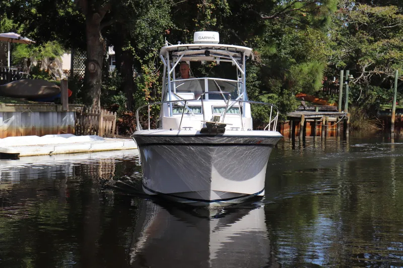 Slide: The Image of 1999 Grady-White Islander 268 boat navigating a calm, tree-lined waterway. - 59