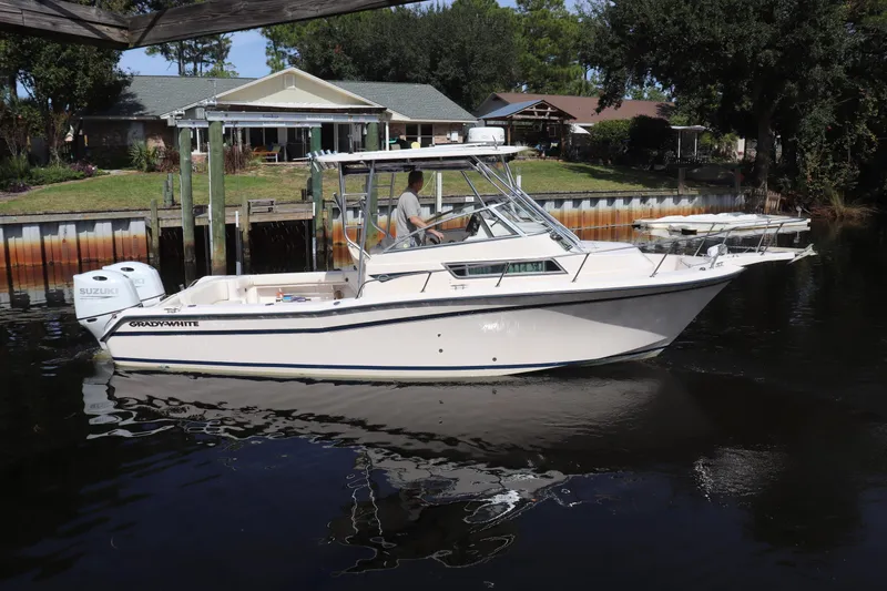 Slide: The Image of 1999 Grady-White Islander 268 boat on calm water near a docked house. - 64