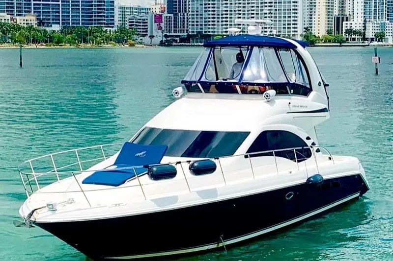 The Image of 2005 Sea Ray 420 Sedan Bridge yacht on turquoise water with city skyline backdrop. - 1