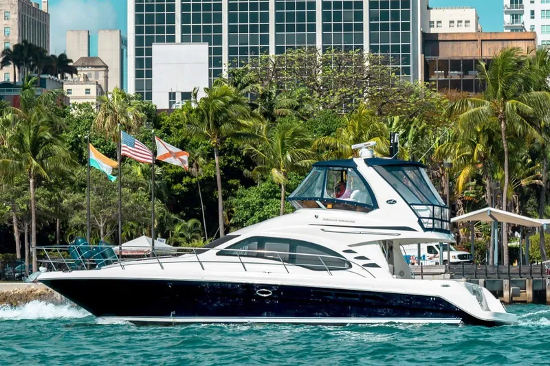 Slide: The Image of 2005 Sea Ray 420 Sedan Bridge yacht cruising near a tropical cityscape. - 14