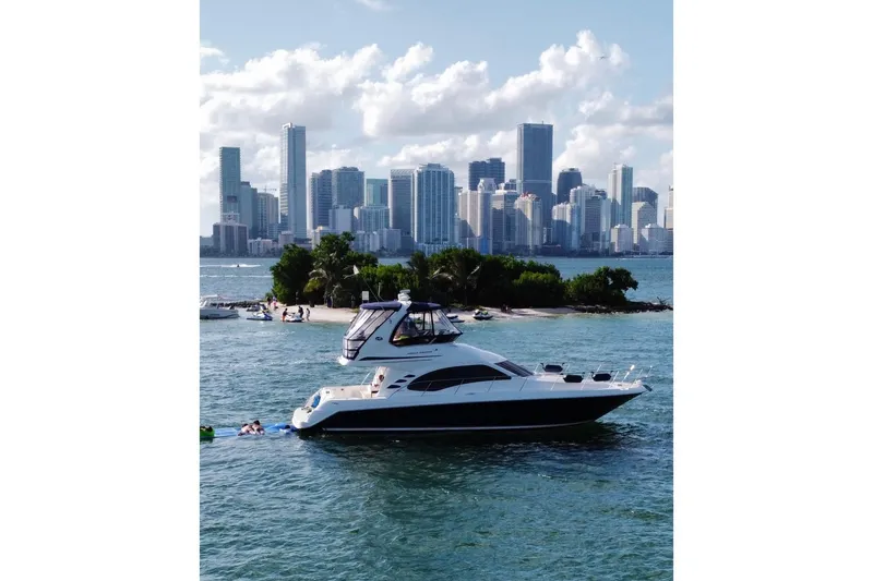 Slide: The Image of 2005 Sea Ray 420 Sedan Bridge yacht cruising near city skyline and small island. - 15