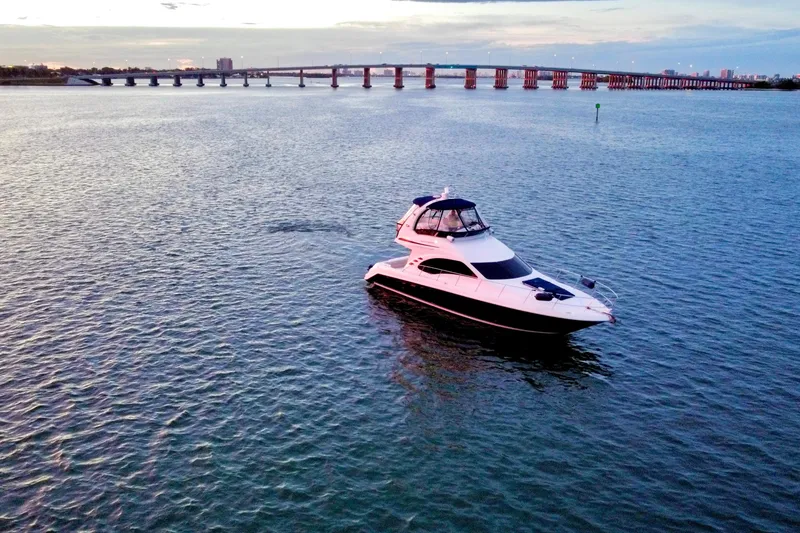 Slide: The Image of 2005 Sea Ray 420 Sedan Bridge yacht on calm waters near a bridge at sunset. - 20