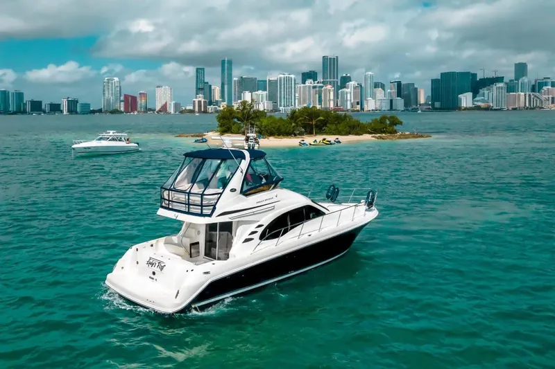 Slide: The Image of 2005 Sea Ray 420 Sedan Bridge yacht cruising near a city skyline and small island. - 5