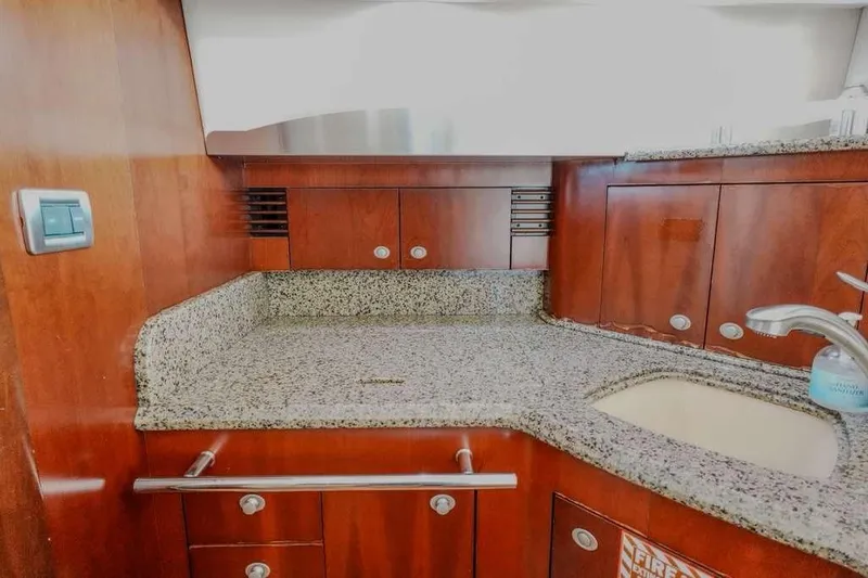 Slide: The Image of 2005 Sea Ray 420 Sedan Bridge kitchen with granite countertops and wooden cabinetry. - 50